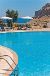 a blue swimming pool with a mountain in the background at Ville Di Lindos in Líndos