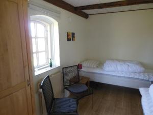 een slaapkamer met een bed en 2 stoelen en een raam bij Nyager Apartments in Ringkøbing