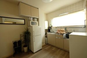 a kitchen with a white refrigerator and a window at COCO Nakameguro 201 in Tokyo