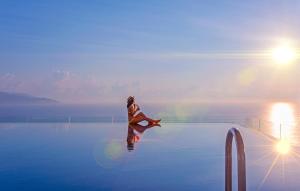 a woman sitting on the edge of a swimming pool at Balcona Hotel Da Nang in Danang