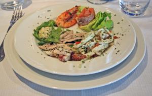 um prato de comida com camarão e salada numa mesa em Hotel Scogliera em Numana