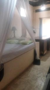 una camera da letto con un letto con tende e un tavolo di Wildebeeste Lamu a Lamu