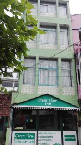 un bâtiment vert et blanc avec un panneau devant lui dans l'établissement Greenview holiday inn, à Munnar