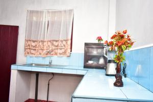 a kitchen with a blue counter top with a vase of flowers at Our House Hikkaduwa in Hikkaduwa