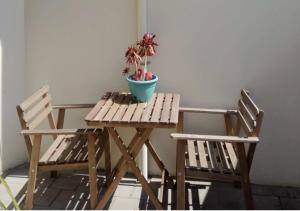 a wooden table with two chairs and a potted plant at Sea & Soul Beachside Apartments in Prevelly