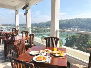 a table with plates of food on a balcony with a view at Kandy Supreme Hotel in Kandy