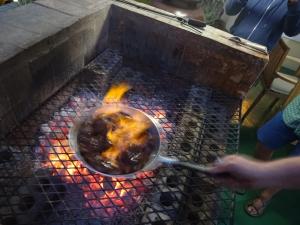 a person cooking food in a pot on a grill at Stadium Guest House in Cape Town