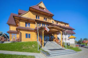 a large wooden house with a gambrel roof at HOTEL*** NAT Bukowina Tatrzańska in Bukowina Tatrzańska