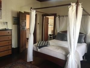 a bedroom with a canopy bed with white curtains at The Inn At The Convent in Taumarunui
