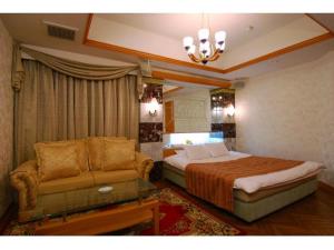 Hotel ShaSha Toyonaka (Adult Only) في تويوناكا: غرفة نوم بسرير واريكة