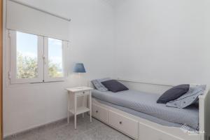 a white bedroom with a bed and a window at Sa Marina in Alcudia