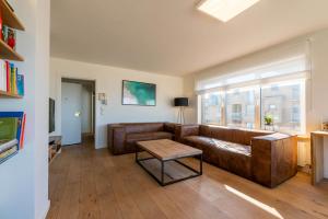 a living room with a leather couch and a table at Seaview Zeebrugge in Zeebrugge