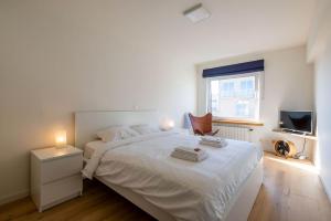 a white bedroom with a bed and a television at Seaview Zeebrugge in Zeebrugge