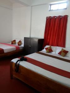 two beds in a room with red curtains at Heritage Lodge in Cherrapunji