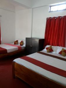 two beds in a room with red curtains at Heritage Lodge in Cherrapunji