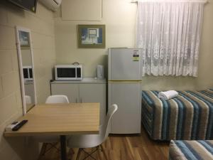 um quarto com uma mesa, um frigorífico e uma cama em Plantation Park Motor Inn em Ayr