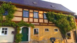 ein altes Haus mit grüner Tür und Fenstern in der Unterkunft Ein Platz für Ruhe und Naturgenuss in Sebnitz