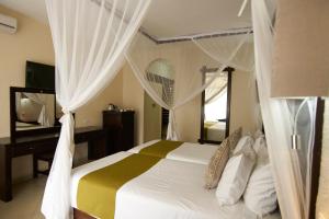 a bedroom with a bed with white curtains and a mirror at Victoria Falls Rainbow Hotel in Victoria Falls