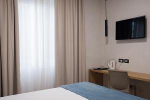 Dormitorio con cama, escritorio y TV en Hotel Doria en Génova