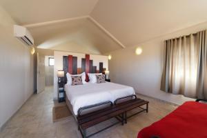 a bedroom with a large white bed and a red couch at Desert Camp in Sesriem