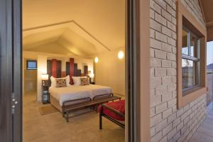 1 dormitorio con cama y pared de ladrillo en Desert Camp en Sesriem