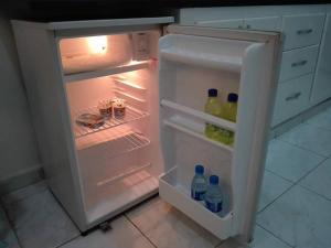 an open refrigerator with bottles of drinks in it at Studio en plein zone touristique avec wifi, IPTV et Clim in Sousse