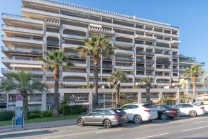 un aparcamiento frente a un gran edificio con palmeras en Center Bay Luxueux appartement avec vue mer 6 eme etage, en Juan-les-Pins