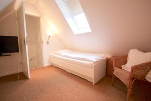 a bedroom with a bed and a window and a chair at Appartement Nordseesonne in Wenningstedt