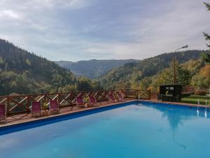 a swimming pool with chairs and mountains in the background at Ośrodek Wypoczynkowy Pod Dębem in Wójtowice