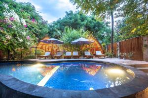 - une piscine avec des chaises et des parasols dans la cour dans l'établissement Manta Dive Gili Air Resort, à Gili Air