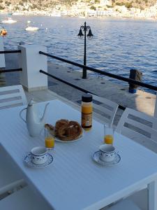 a table with a plate of bread and two glasses of orange juice at Sea front Villas Danezis in Symi