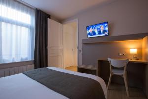 リールにあるArembault Appart Hôtelのベッド、デスク、テレビが備わるホテルルームです。