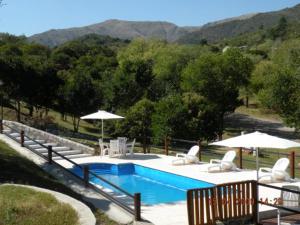 a swimming pool with chairs and umbrellas at Cabañas Los Gauchitos in La Falda