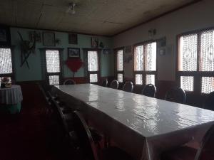 einen großen Tisch in einem Zimmer mit Stühlen und Fenstern in der Unterkunft Khunjerab Hotel Sost in Gircha