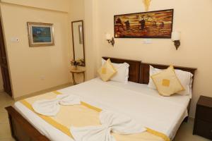 um quarto com uma cama com lençóis brancos e almofadas em Fort Thari Inn em Galle
