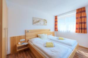 a bedroom with a large white bed with a window at Apart Bellevue in Pettneu am Arlberg