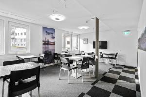 a dining room with tables and chairs and a tv at Brygga Gjestehus in Harstad
