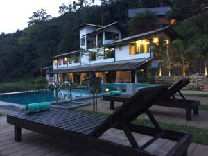 a house with a swimming pool and a wooden bench next to a house at Explore Sinharaja Rain Forest Tour Camp in Dombagoda