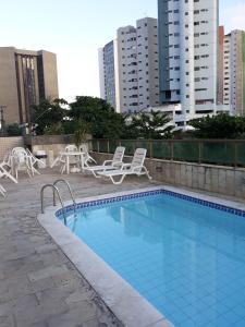 una piscina con sillas, mesas y edificios en Apto próximo praia Recife, en Recife