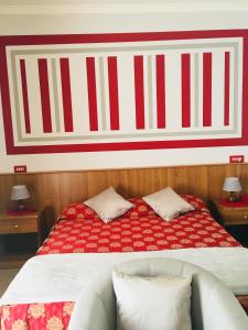 a bedroom with a bed with a red and white striped wall at Hotel Facioni in Pomezia