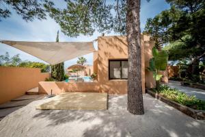 una casa con un árbol delante de un edificio en La Villa, en Cala Vadella