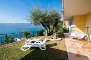 a pair of white lounge chairs on the grass next to a house at Villa Margherita in Torri del Benaco
