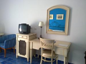 a room with a desk with a tv and a mirror at Hotel Rocce Azzurre in Lipari +28 photos