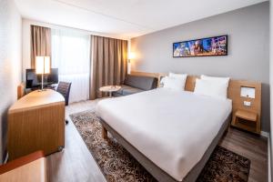 Habitación de hotel con cama grande y sofá en Novotel Eindhoven en Eindhoven