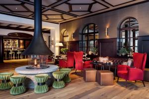 a lobby with a fireplace and red chairs at Mont Cervin Palace in Zermatt