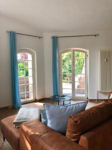 een woonkamer met een bank en 2 ramen bij Ferienwohnung am Wasser Villa Graf von Pfeil in Dresden