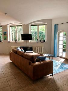 een bruine bank in een woonkamer met ramen bij Ferienwohnung am Wasser Villa Graf von Pfeil in Dresden