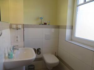 a bathroom with a sink and a toilet and a window at Exkl_ App_ Buhne_ Kamin_ W_LAN_ 25 in Börgerende-Rethwisch