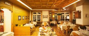 ein Esszimmer mit weißen Tischen und Stühlen und Tischsucher in der Unterkunft Hotel Costabella in Passo San Pellegrino