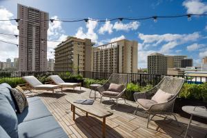 a patio with chairs and tables on a rooftop at The Surfjack Hotel & Swim Club in Honolulu